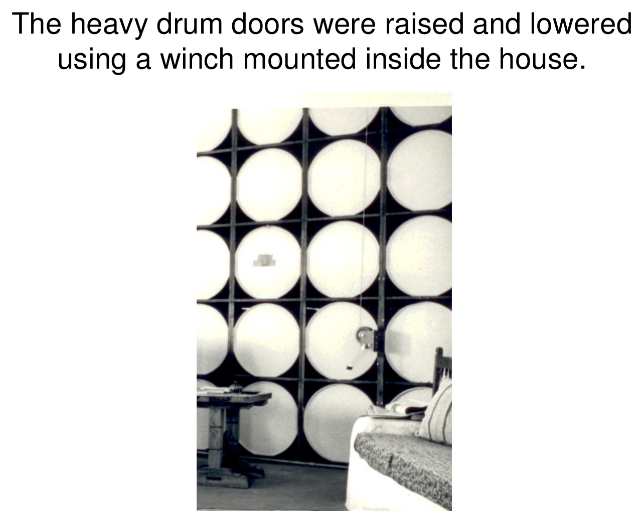 Interior photograph of a wall of white-capped water drums; the heavy drum doors were raised and lowered with a winch mounted inside the house