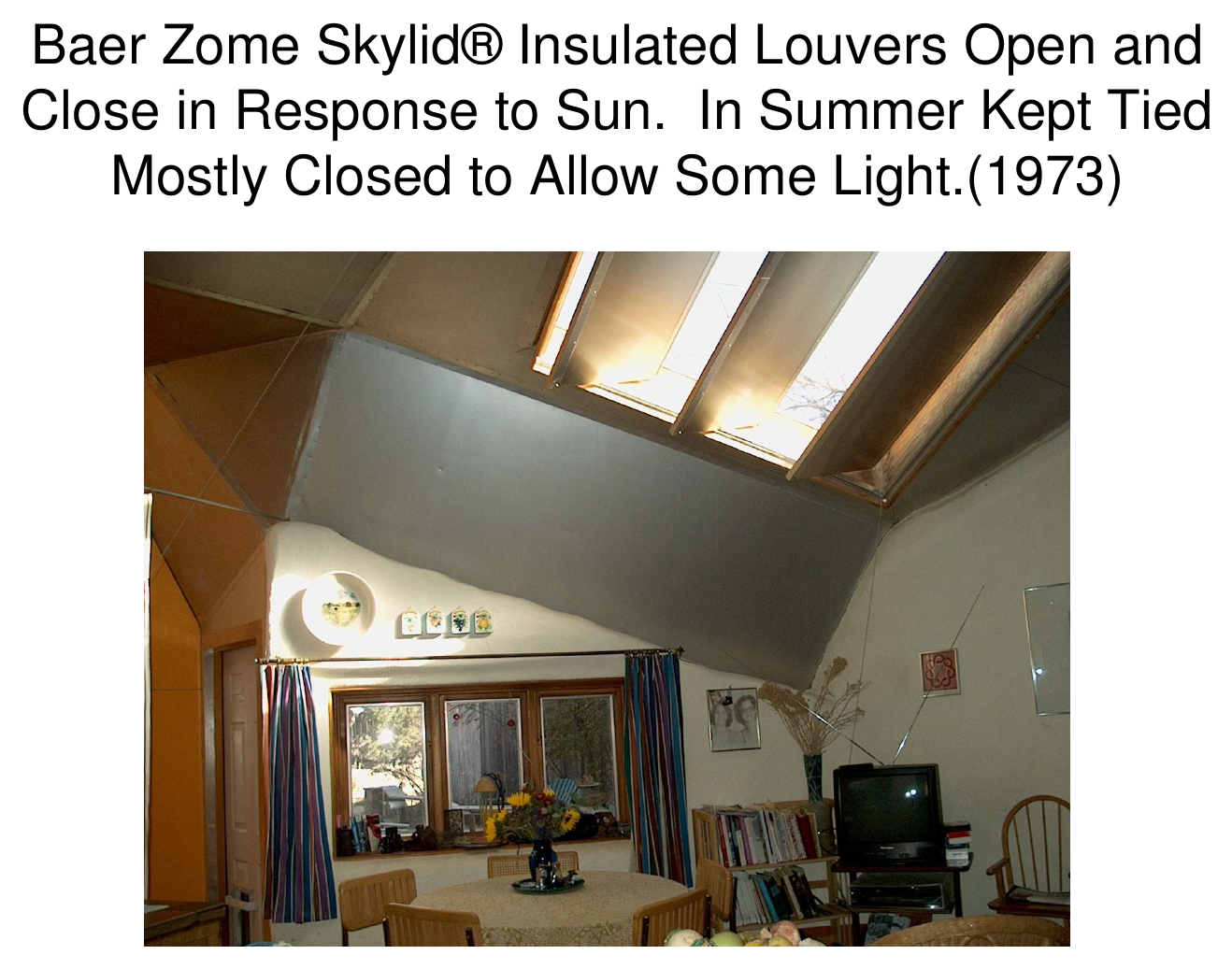 Interior photograph looking toward a sloped ceiling with Baer Zome Skylid insulated louvers, a living room below