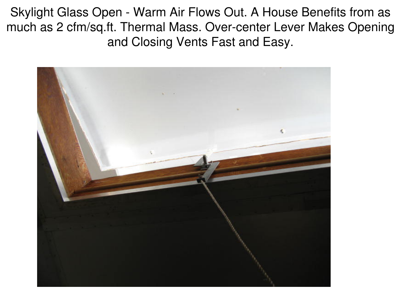 Photograph of an open skylight with the glass propped open by an over-center lever, warm air flowing out