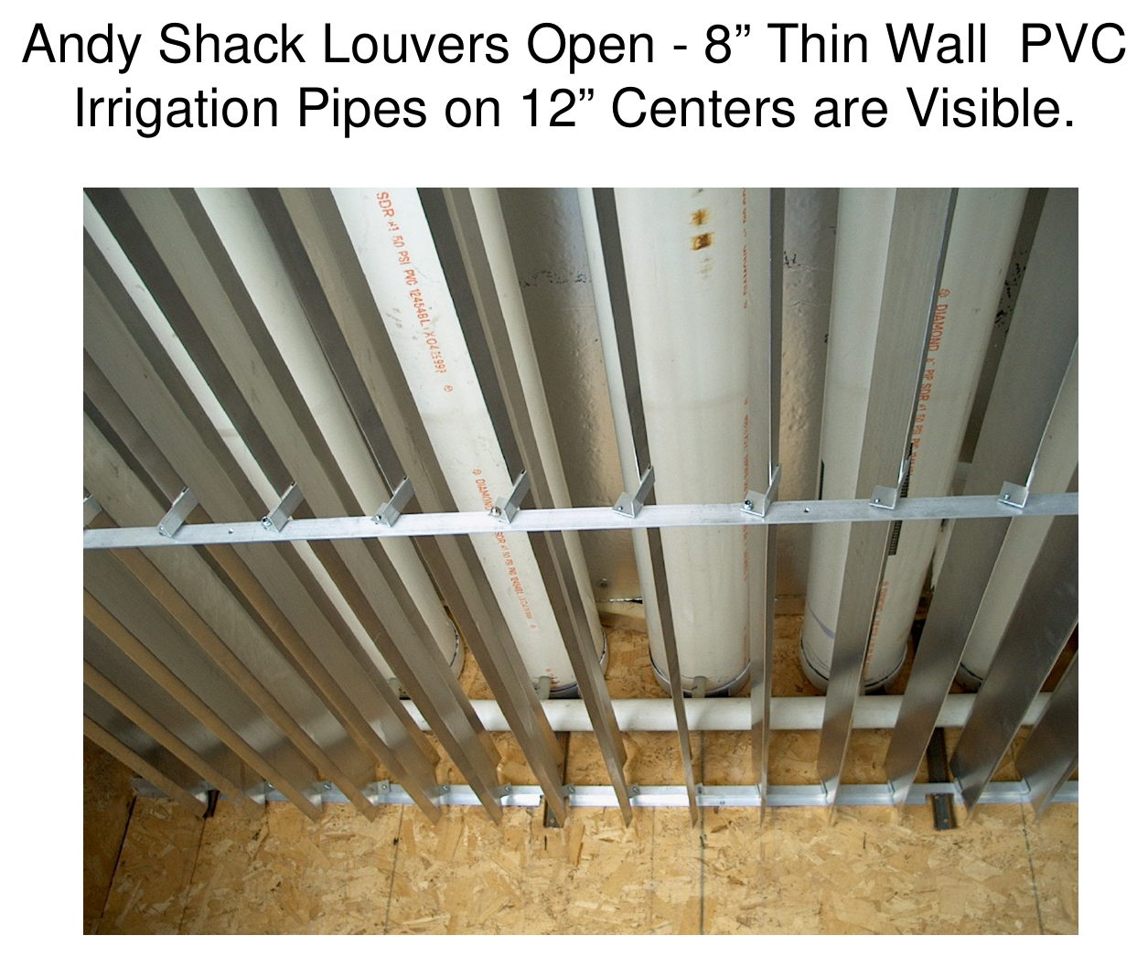 Interior ceiling photograph of the Andy Shack with louvers open, showing 8-inch thin-wall PVC irrigation pipes on 12-inch centers