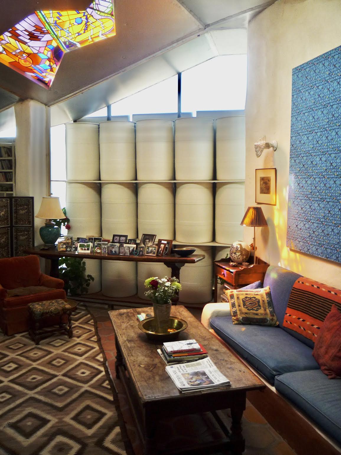 Interior of Steve Baer's zome home showing white plastic drum wall thermal mass storage, stained glass skylight, and living room